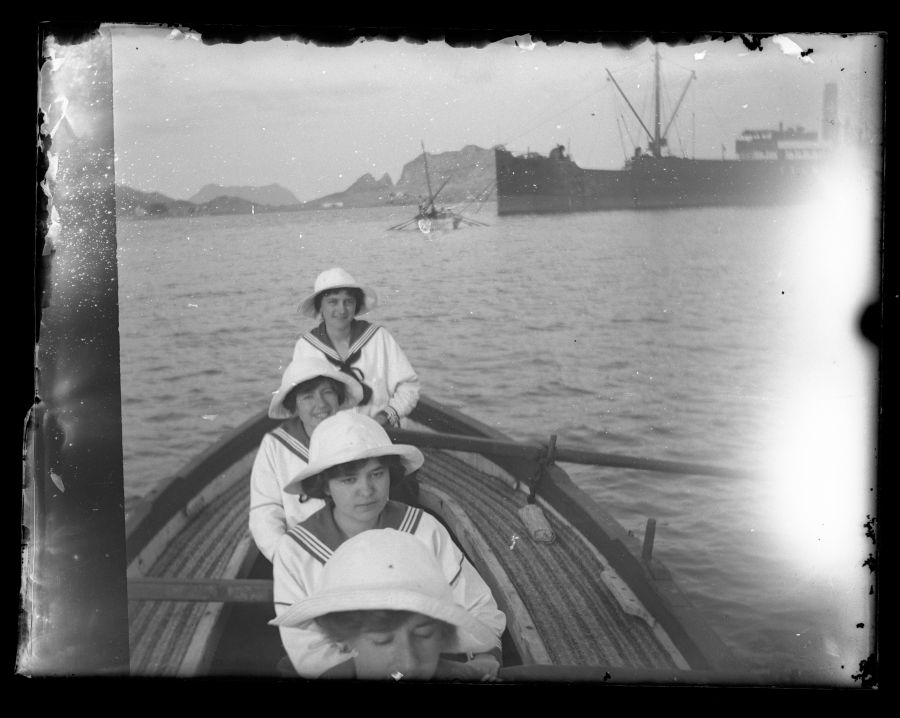 Grupo de chicas con vestido marinero en una embarcación de recreo de remos.