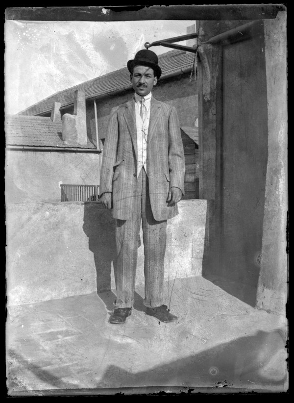 Retrato de cuerpo entero de un hombre con traje y bombín en la azotea de un edificio