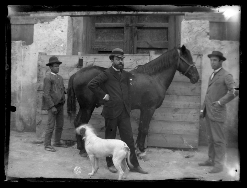 Retrato de tres hombres en exterior junto a un caballo y un perro