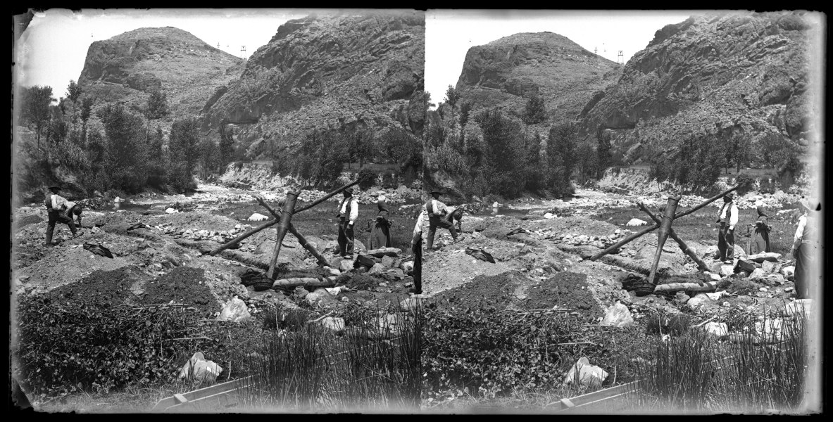 Un grupo de campesinos o mineros en torno a la boca de un sondeo o pozo, en el cauce de un río de montaña