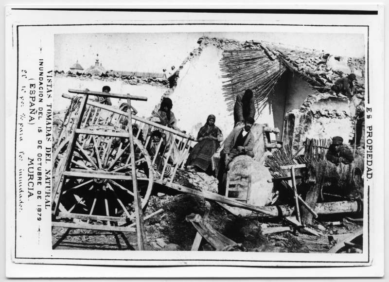Reproducción de una fotografía de una familia con su casa devastada por los efectos de la Riada de Santa Teresa.