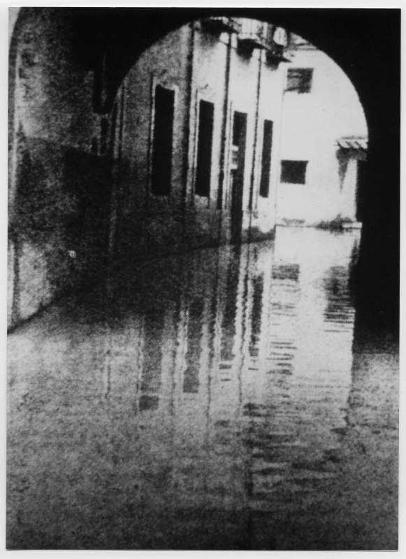 Reproducción de una fotografía del arco de Camachos y calle de acceso a los Molinos inundados.