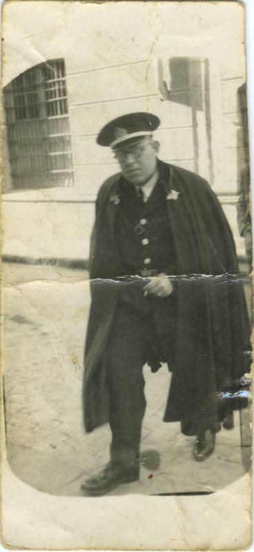 Retrato de agente uniformado con capote en la calle.