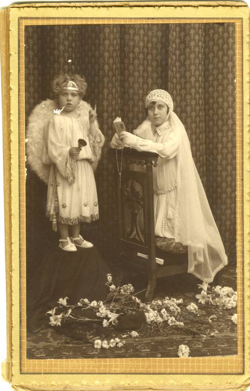 Retrato de niña de primera comunión, acompañada de otra vestida de ángel.