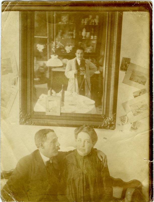 Retrato de una pareja, con fotógrafo reflejado en el espejo.