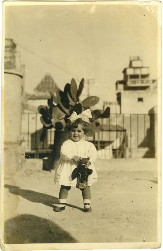Retrato de niña con lazo jugando en la azotea.
