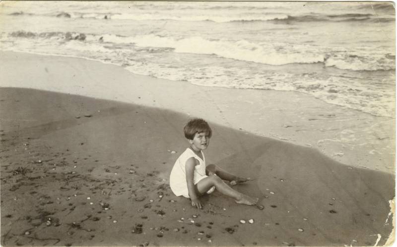 Retrato de una niña sentada en la playa.