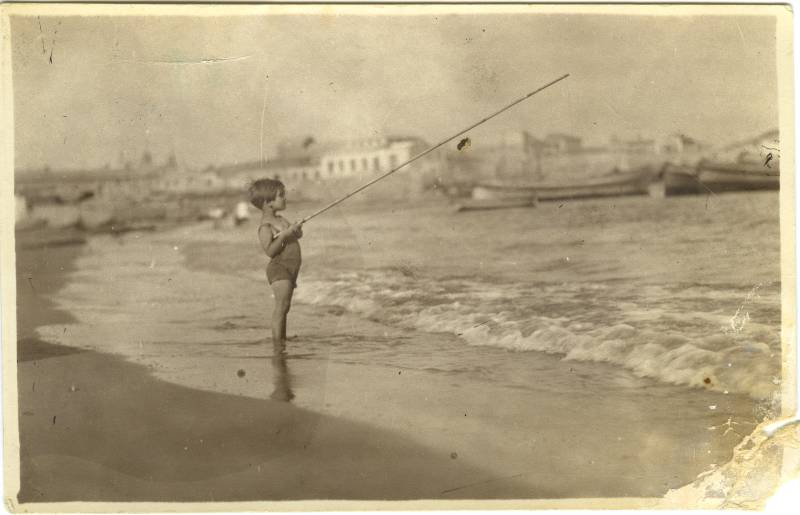 Retrato de una niña en la playa con caña de pescar.