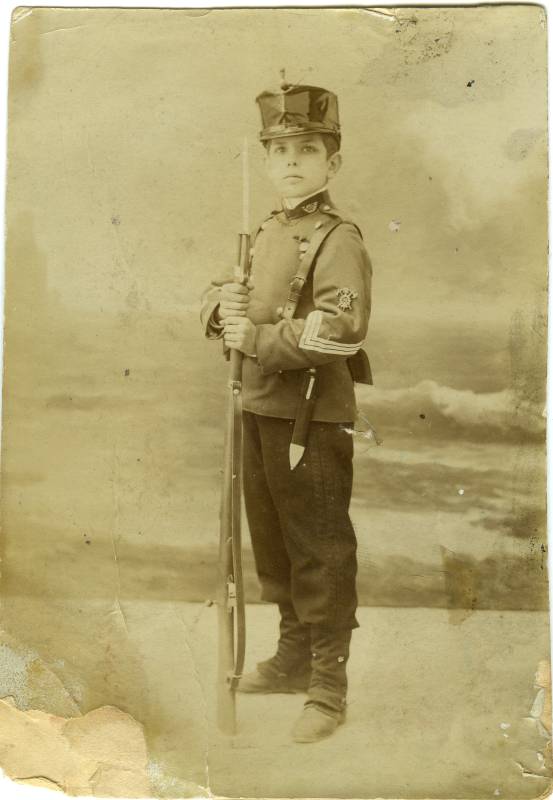 Retrato de un niño vestido de soldado de infantería, con fusil y balloneta calada.