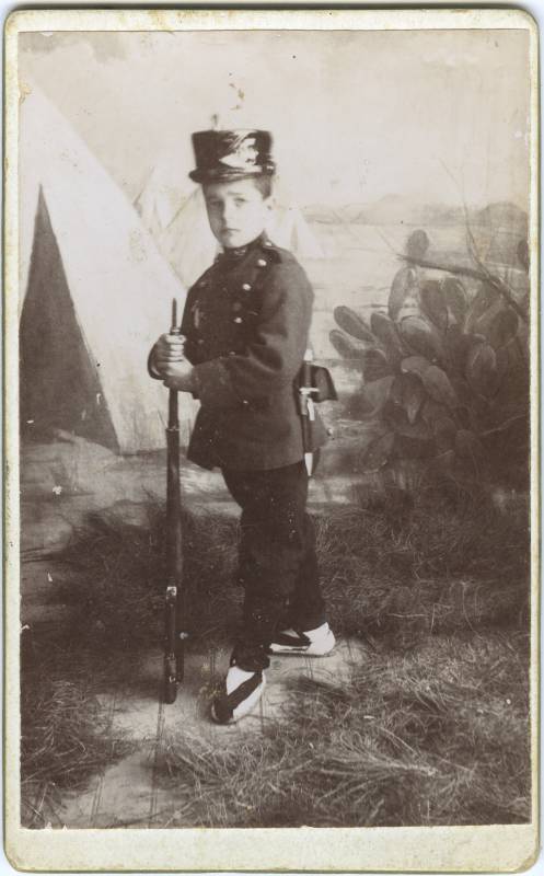 Retrato de niño vestido de soldado de infantería, con fusil.