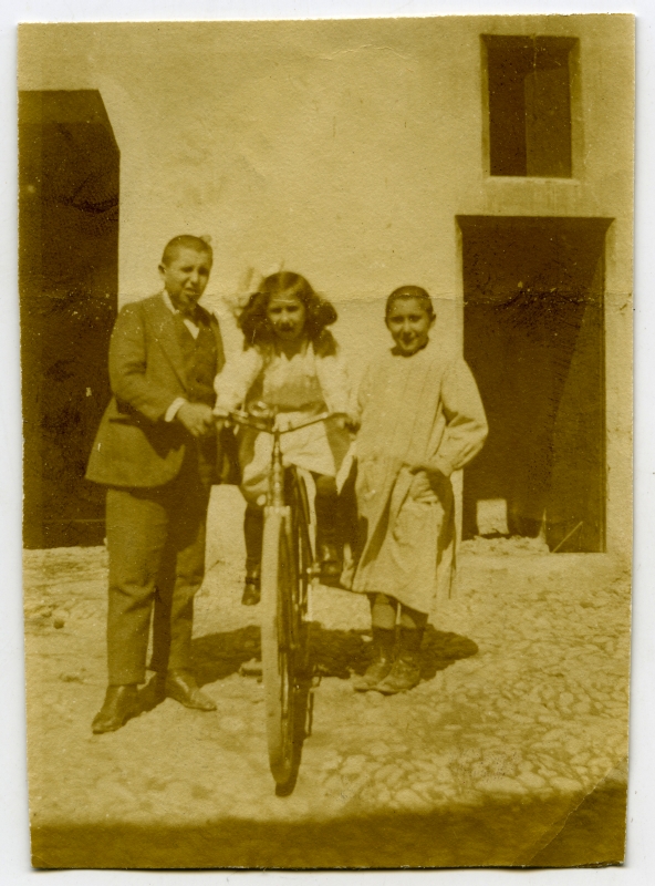 Retrato de los hermanos Raimundo, Enriqueta y Antonio Moxó Ruano con una bicicleta
