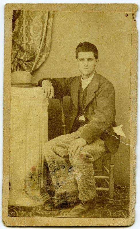 Retrato de hombre joven sentado en una silla.