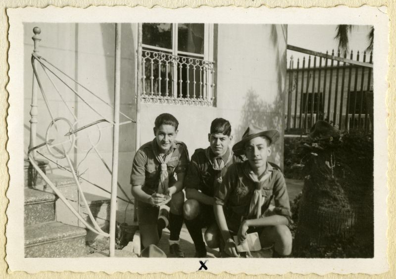 Retrato de tres exploradores en la puerta de una vivienda