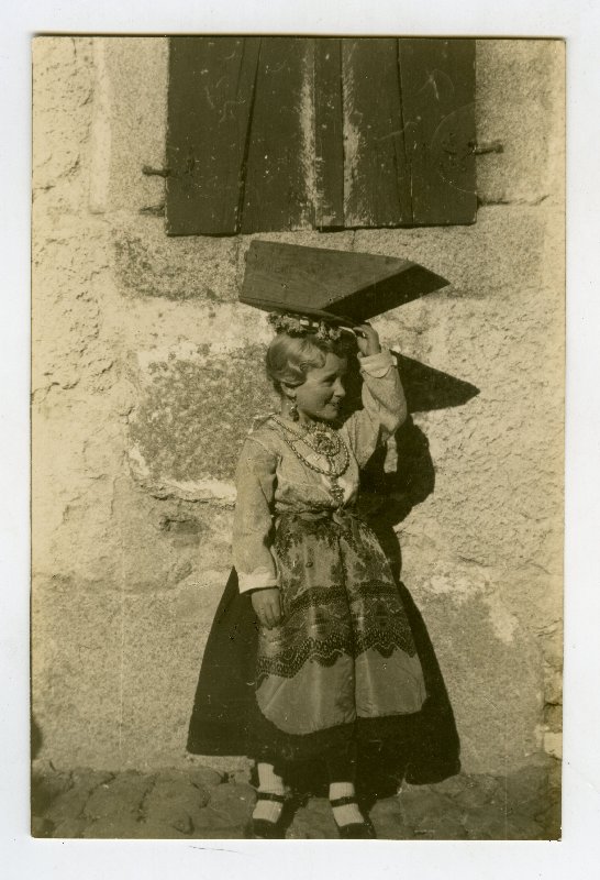 Niña con traje tradicional y una media fanega sobre la cabeza en La Alberca, Salamanca