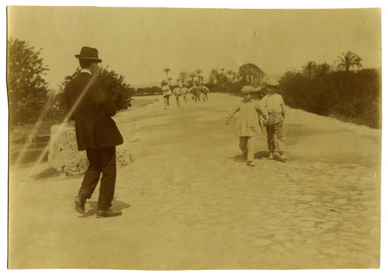 Un hombre con traje y sombrero y varios niños paseando por el paseo del Malecón de Murcia