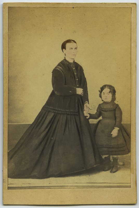 Retrato de estudio de una mujer y una niña de pie vestidas de negro