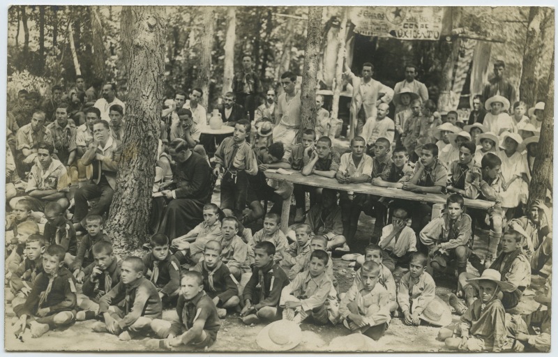 Un grupo de exploradores contemplando algún acto o espectáculo en el bosque
