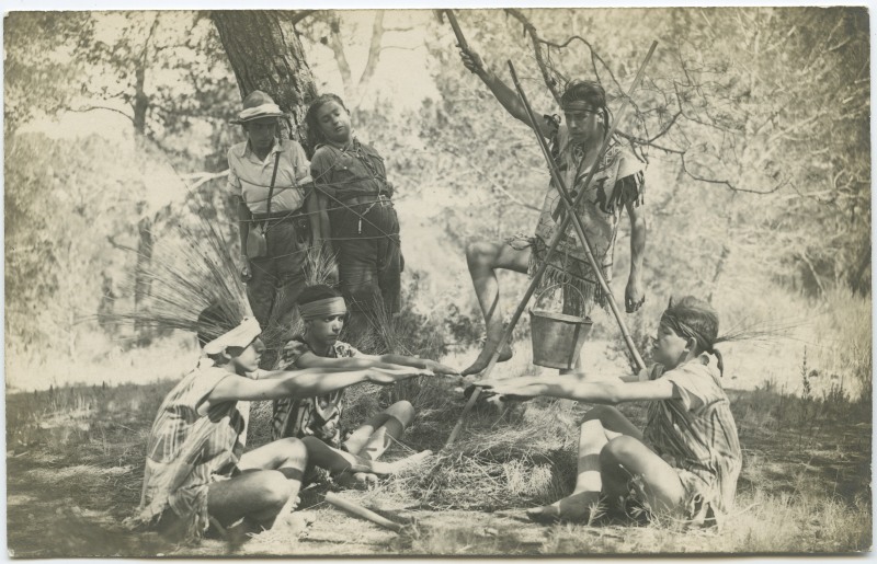 Varios exploradores disfrazados de indios simulan haber capturado y atado a un arbol a dos de sus compañeros