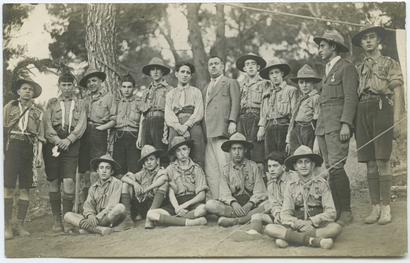 Un grupo de exploradores junto a dos hombres vestidos de traje