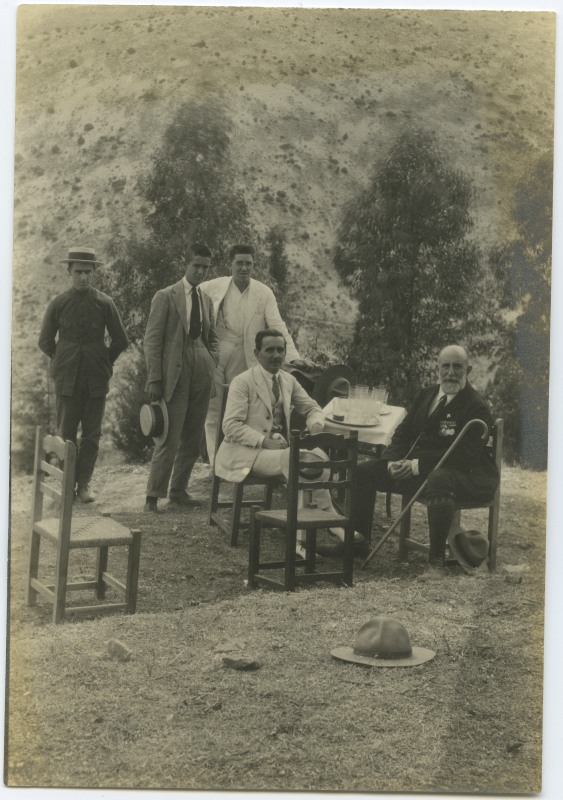 Isidoro de la Cierva sentado en una mesa con vasos en el campo junto a varias personas