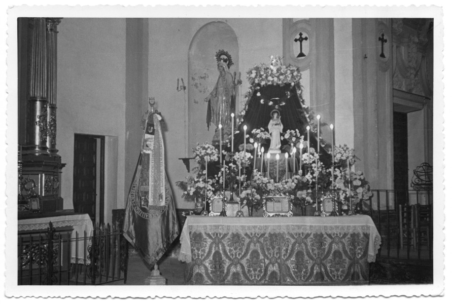 Altar con velas y estandarte del Orfeón Murciano Fernández Caballero en una iglesia.