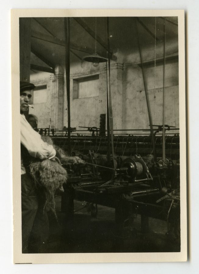 Operario hilando esparto con una máquina eléctrica en el interior de una fábrica