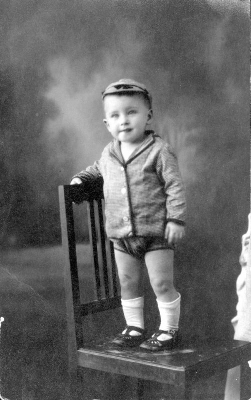 Retrato de niño de pie sobre una silla.