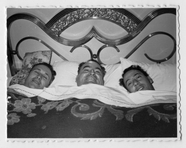 Francisco Suárez posa con dos amigos acostados en una cama de matrimonio