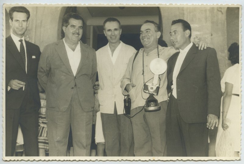 Retrato de Francisco Suárez equipado con cámara y flash y acompañado por varios amigos