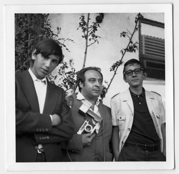 Retrato de Antonio González equipado con cámara y acompañado por dos adolescentes