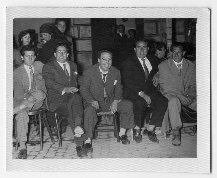 Retrato de Antonio Suárez sentado con varios amigos en sillas dispuestas en la calle durante un día de procesión de Semana Santa