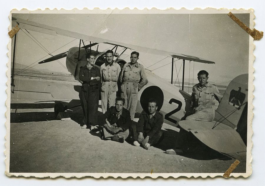 Eduardo Batán posa con varios compañeros junto a un avión biplaza.