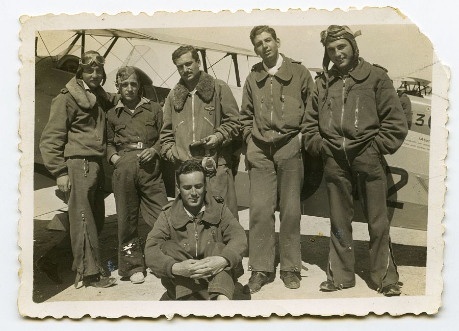 Eduardo Batán posa delante de un biplano junto a un grupo de pilotos de uniforme.