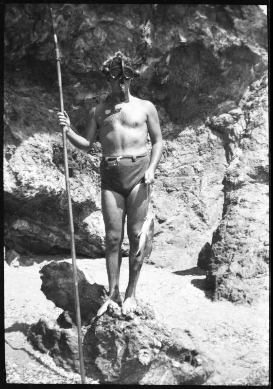 Amós Blanco Rodríguez posando sobre una roca con gafas de buceo, arpón y un pescado.