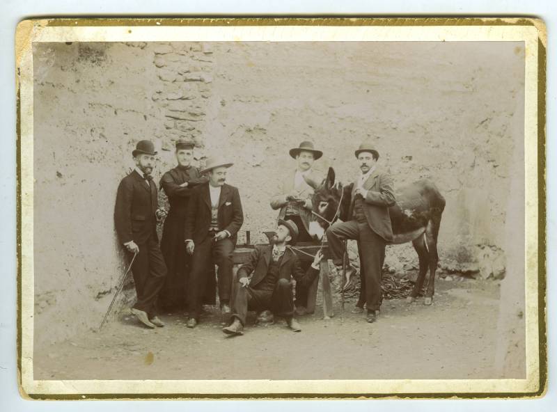 Retrato de un grupo de hombres en un corral posando con un burro