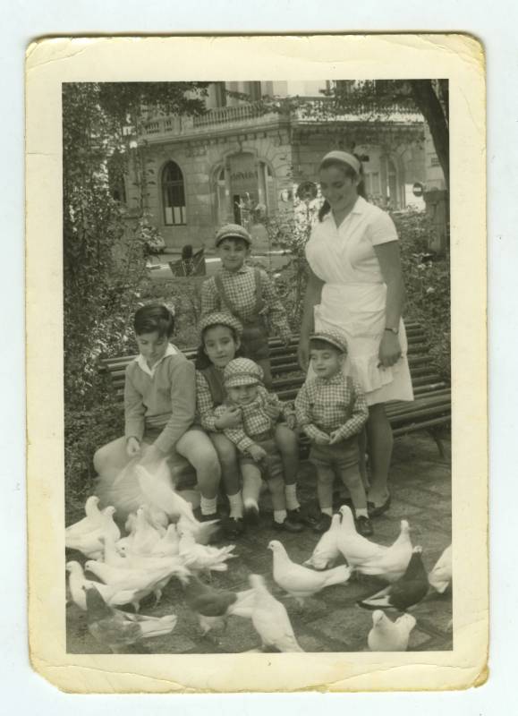 Retrato de los hermanos Cutillas de Mora con una niñera, rodeados de palomas, en un jardín de Alicante