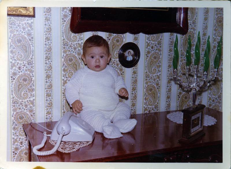 El bebé Enrique Barnuevo Calvo sentado sobre un aparador de la casa de Jumilla
