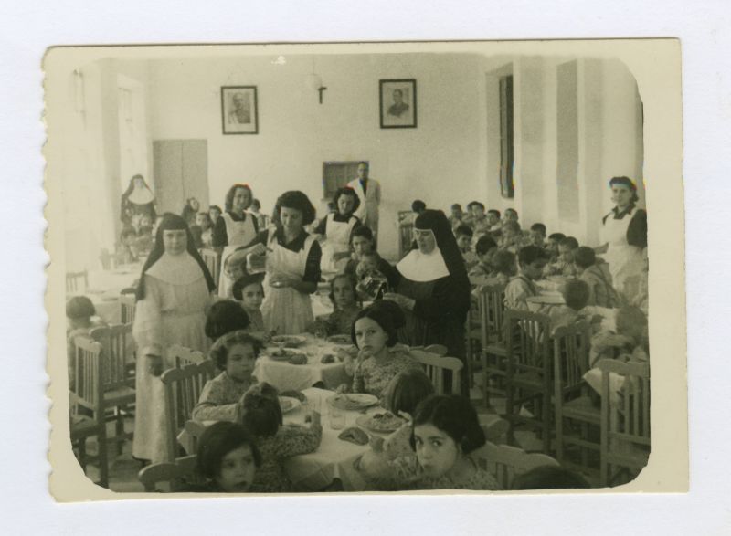 Niños comiendo en el comedor del Asilo Santa Teresa de Jesús de Abarán, con religiosas y señoritas de Auxilio Social