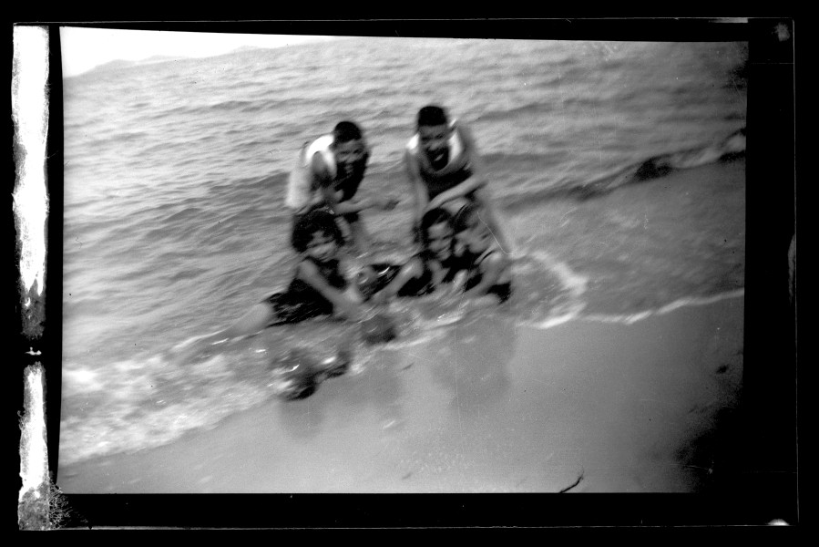 Retrato desenfocado de un grupo de niños bañándose en la orilla de la playa